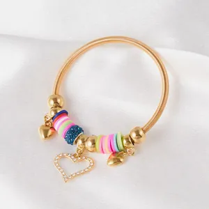 Detail of gold spring bracelet with colorful beads and rhinestone heart charm