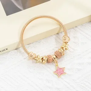 Detailed shot of golden spring coil bracelet with pink enamel starfish and heart charms