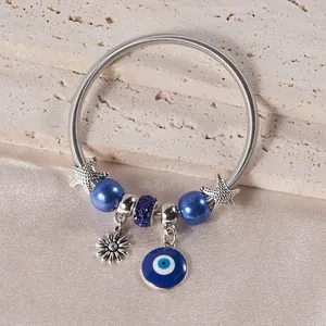 Close-up of silver beaded bracelet with blue Evil Eye, starfish, and daisy charms