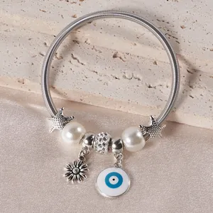 Detailed view of silver spring bracelet with evil eye charm, starfish, and pearls