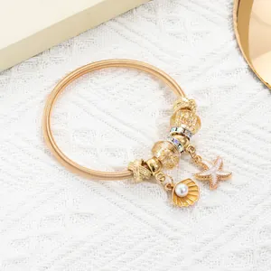 Detailed macro view of golden spring bracelet with sea shells, star fish and pearl charms