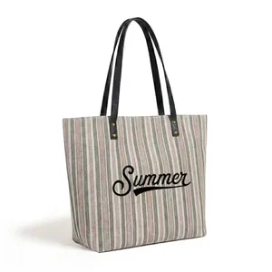 Detailed side view of large striped tote bag with Summer print and leather handles