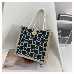 Detail of canvas tote bag with floral checkerboard pattern and wooden button closure