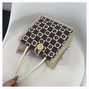 Detail of floral checkerboard canvas tote with wooden button closure and braided handle