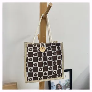 Close-up of small jute tote bag featuring floral checkerboard pattern and wooden button