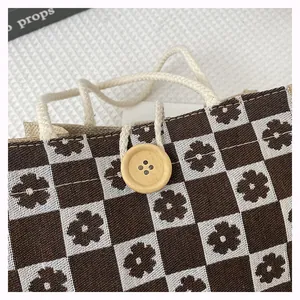 Detail of floral checkered canvas tote bag with wooden button closure and rope handles