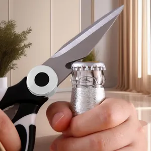 Multifunctional stainless steel kitchen shears opening a glass bottle cap in use