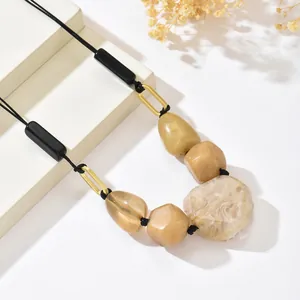 Close-up of bohemian resin beads with marble texture and golden rings on black cord
