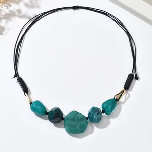 Detail of vintage necklace featuring five green resin stones on a black cord strap