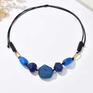 Macro detail of bohemian necklace featuring blue marble beads and black woven cord