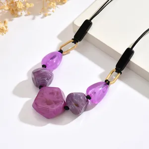 Detail of purple resin beads with marble texture and golden metal links on a necklace