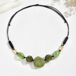 Macro detail of ethnic necklace with olive green resin beads and golden rings