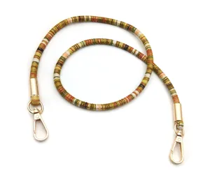 Close-up of bohemian multi-color striped woven strap with gold lobster clasps and metal tubes
