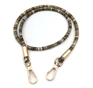 Close-up of grey and gold braided shoulder strap with large lobster claw clasps