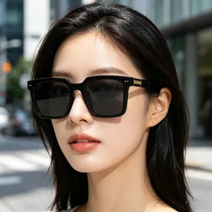 Fashionable model wearing black square oversized sunglasses with gold metal detail
