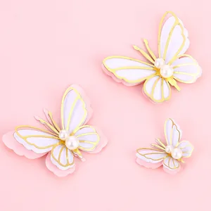 Elegant 3D butterfly cake toppers with gold foil edges and pearls on pink background