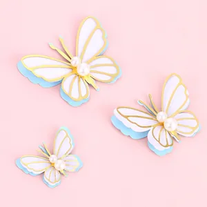 3D butterfly cake toppers with pearls and gold edges on light pink background