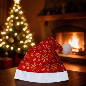 Bonnet de Noël en velours rouge avec flocons dorés sur une table en bois festive