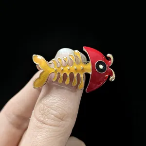 Macro detail of cartoon fishbone brooch with vibrant red and yellow enamel finish