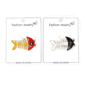 Macro detail of cute fishbone enamel brooches in red and black on jewelry cards