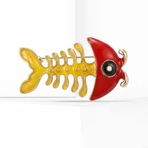 Detailed macro view of yellow fishbone brooch with red enamel head and gold metal finish