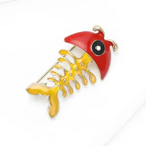 Detailed view of creative fishbone brooch with red enamel head and golden fish body