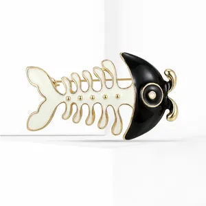 Macro shot of minimalist fishbone brooch with black and white enamel and golden plating