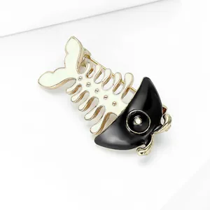 Detail showing the golden pin clasp on the back of a black and white fishbone brooch