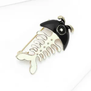 Macro detail of cartoon fishbone brooch featuring black enamel and golden alloy pin closure