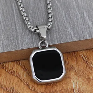 Macro shot of silver octagonal pendant with black enamel inlay on steel box chain