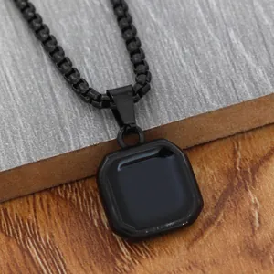 Macro detail of an octagonal black pendant with a sleek box chain on stone background