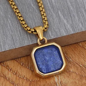 Macro view of a gold square lapis lazuli pendant with thick box chain on a stone surface