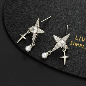 Close-up of star stud earrings with pavé crystals and hanging white round pearl drops