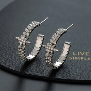 Close-up of C-shaped star earrings with pavé zircons on black leather display