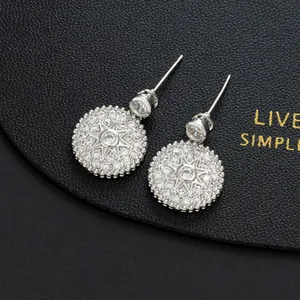 Macro shot of silver starburst earrings with white zircon on black leather background