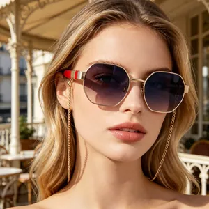 Close-up of oversized polygon sunglasses with gold chain on a model in a sunny cafe