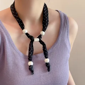 Detail van zijden sjaal ketting met polkadots en grote witte parel decoraties