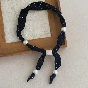 Detail van de polkadot sjaalketting met grote witte parels en gesp met marmerpatroon