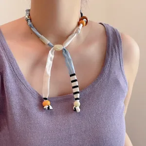 Detail van stoffen kralenketting met blauw-witte strepen en getextureerde kralen