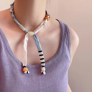 Gedetailleerde close-up van een kleurrijke kralen sjaalketting op de hals van een model