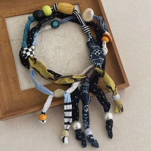 Artistiek detail van een boho sjaalketting met kleurrijke kralen en diverse stoffen patronen