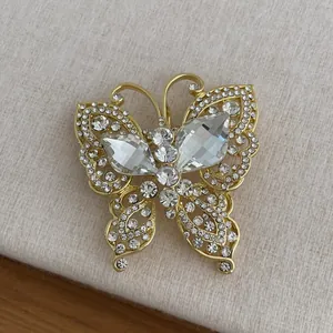 Vista macro de un broche de mariposa dorado con circonitas sobre fondo de tela beige