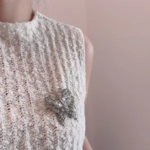 Detalle de un broche de mariposa con circonitas brillantes en una prenda de punto