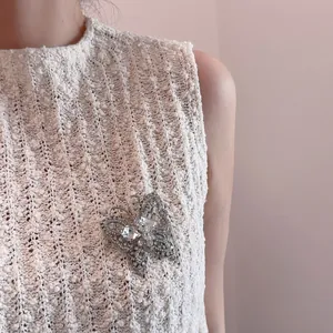Elegante broche de mariposa plateado con cristales brillantes en un chaleco de punto blanco