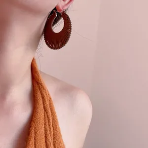 Détail de boucles d'oreilles bohèmes avec corde tressée marron et bordure perlée argentée