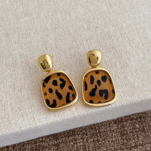 Nahaufnahme von Harzohrringen mit Leopardenmuster, Goldbasis und Vintage-Muster