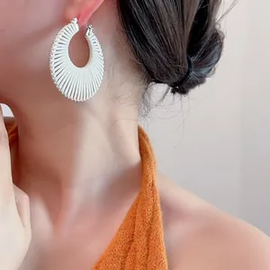 Détail des boucles d'oreilles créoles plissées blanches avec bordure perlée argentée