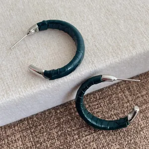 Détail de boucles d'oreilles en C vert foncé avec texture cuir crocodile et touches argent