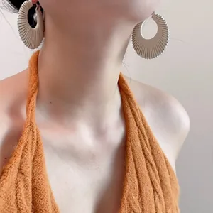 Détail de boucles d'oreilles plissées crème en forme d'éventail portées par un mannequin