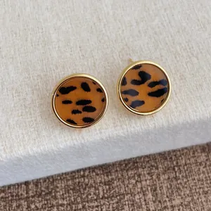 Nahaufnahme goldener runder Ohrstecker mit Leopardenmuster im edlen Vintage-Design